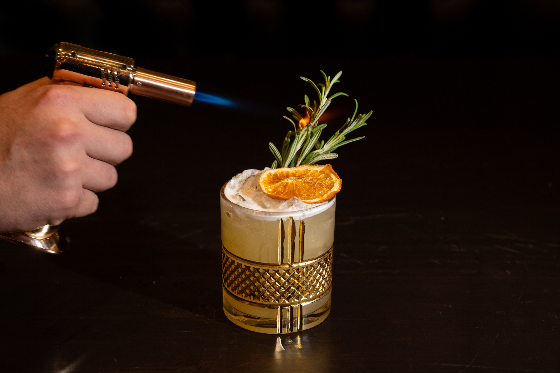 Smoked cocktail with flamed rosemary and citrus garnish